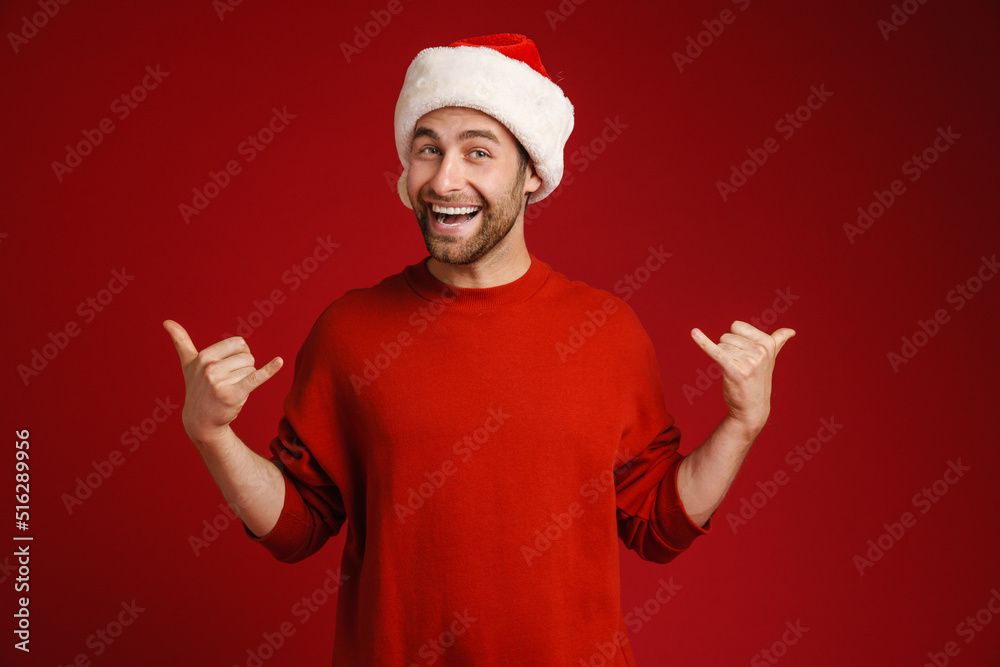 Young white man wearing santa hat gesturing and laughing at camera Young white man wearing santa hat gesturing and laughing at camera