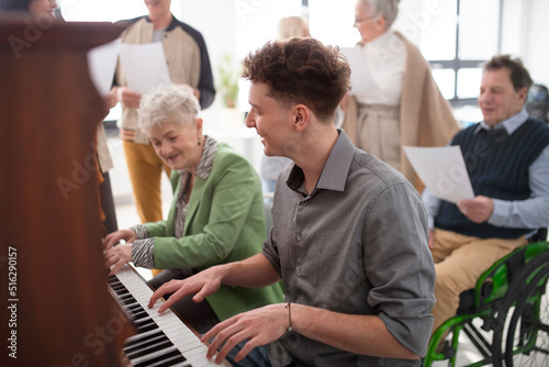Senior woman with young teacher playing at piano in choir rehearsal Fototapet