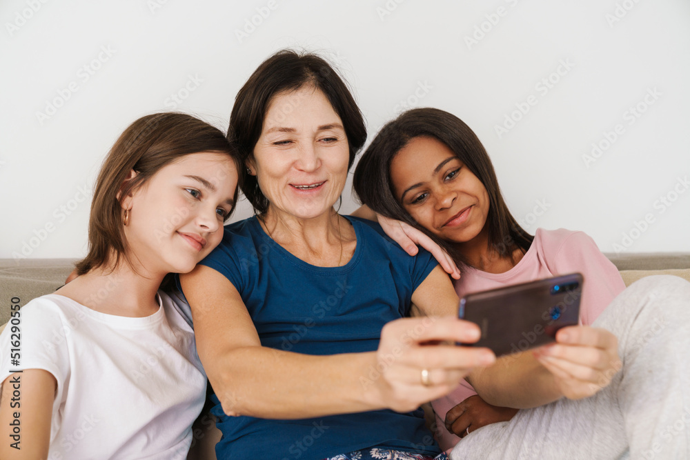 White woman and her daughters taking selfie photo while resting on couch White woman and her daughters taking selfie photo while resting on couch