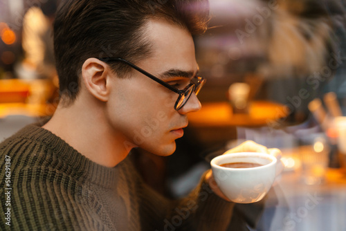 Young white brunette man wearing eyeglasses drinking coffee in cafe