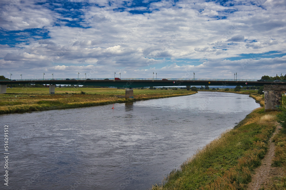 Fototapeta premium Blick auf die moderne Elbebrücke (Straßenbrücke) über den Flusslauf unter ausdrucksstarkem Wolkenhimmel bei Torgau, Sachsen, Deutschland