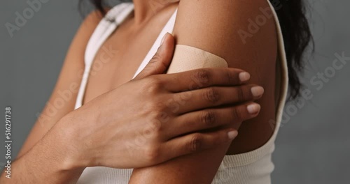 Bi racial female gently toughing her band aid with a smile