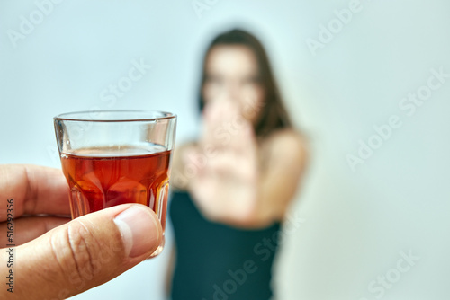 The girl is offered a glass of alcohol, but she categorically refuses. The concept of giving up alcohol.