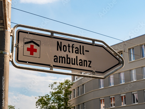 Notfallambulanz sign in Germany (emergency department). Signpost guiding to the entrance of a hospital. Urgent health treatment for accident victims. Sunset light is shining on the metal plate.