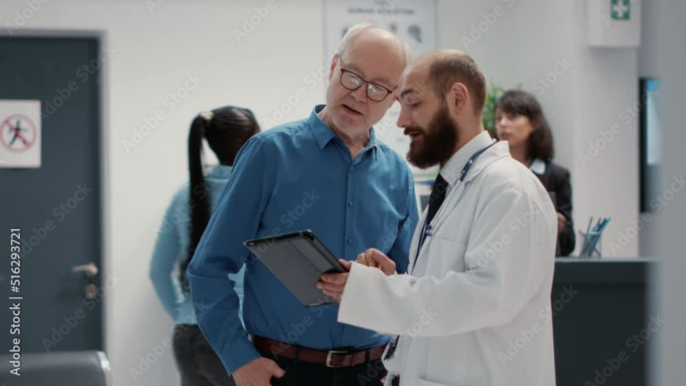 Male physician doing consultation with retired man in hospital reception lobby, talking about healthcare in waiting room. People chatting about disease in waiting area at medical clinic. Male physician doing consultation with retired man in hospital reception lobby, talking about healthcare in waiting room. People chatting about disease in waiting area at medical clinic.