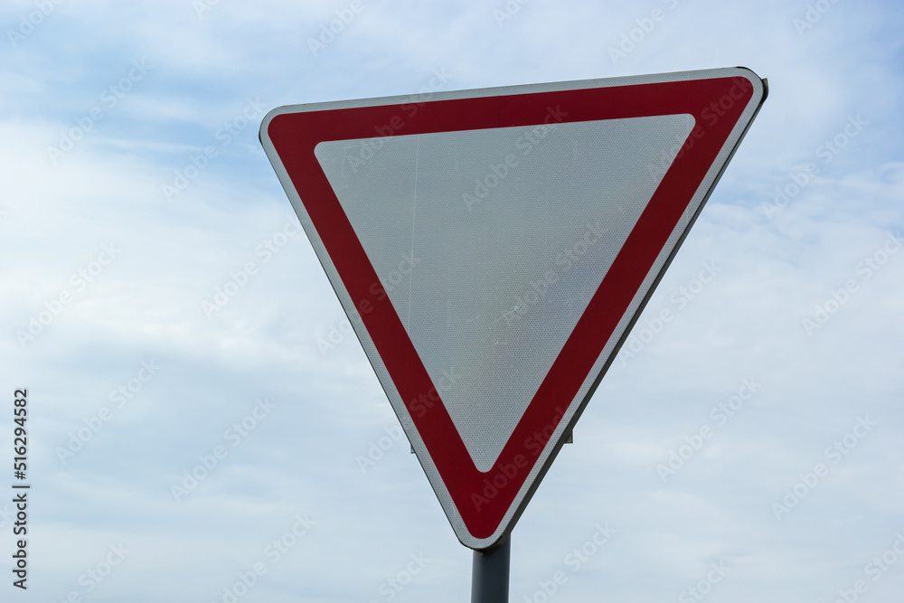Road sign against the sky. White triangle with red border. Signal, Give way. Summer day Road sign against the sky. White triangle with red border. Signal, Give way. Summer day