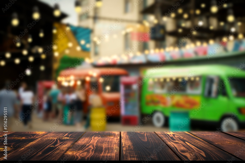 Wooden table on blurred hipster street food urban market background. Empty placement desk for product or food and drink. Lifestyle concept. Selected focus 