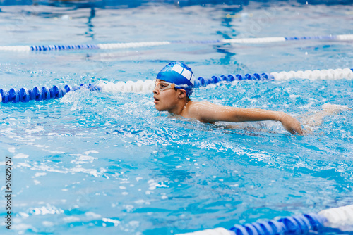 latin child boy swimmer wearing cap and goggles in a swimming training at the Pool in Mexico Latin America 