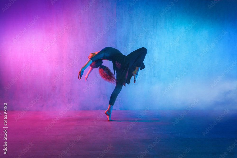 Modern dance girl dancer dancing in neon light doing gymnastic exercises in studio, copy space. - obrazy, fototapety, plakaty 