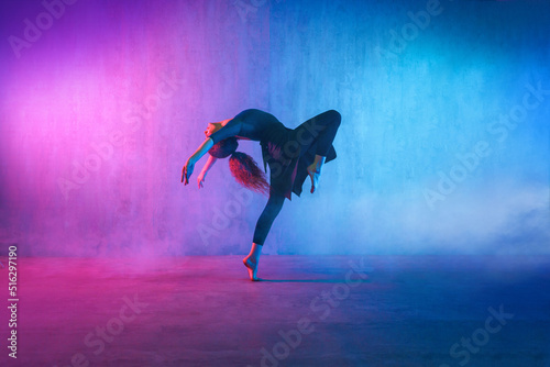 Fototapete Modern dance girl dancer dancing in neon light doing gymnastic exercises in studio, copy space