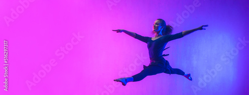 Modern dance girl dancer jumping up dancing in neon light doing gymnastic exercises in studio, wide banner, copy space.