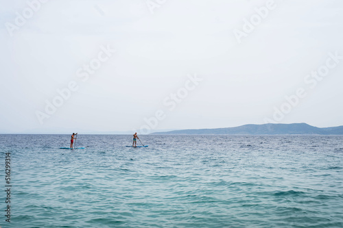 Men spending leisure time while enjoying paddling on SUP in sea during summer. Summer vacation concept.
