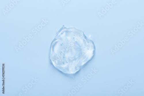 Clear transparent cosmetic skin care gel serum smear with bubbles isolated on blue background top view