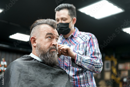 An adult man with a mohawk in a barbershop. The master An adult man in a barbershop with a beard and a mohawk.