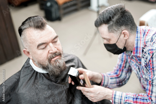 Barbershop. The master works with the beard of an adult man