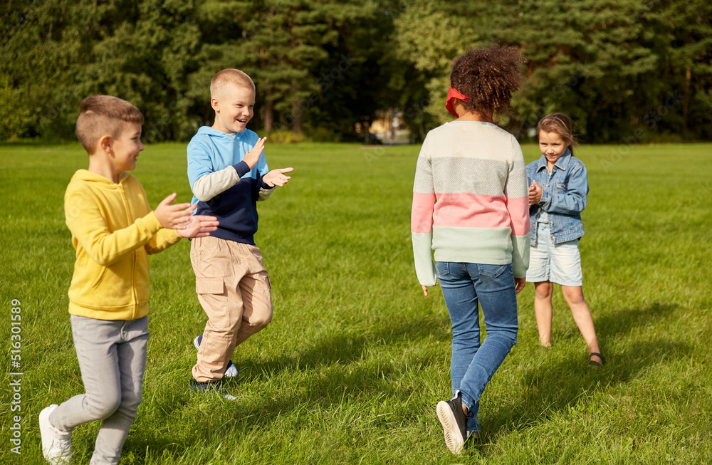 Fototapeta premium childhood, leisure and people concept - group of happy children playing tag game and running at park