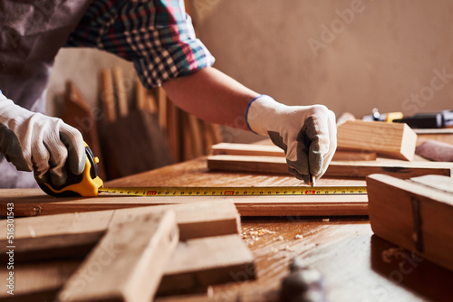 Female craftsmen use tape measure to assemble wooden pieces. Construction Worker hold ruler. Professional carpenter at work measuring wooden planks.
