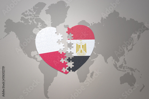 puzzle heart with the national flag of egypt and poland on a world map background.Concept.