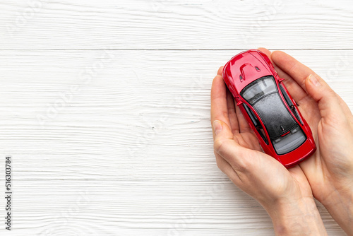Toy car in hands, top view. Car insurance or driving safety concept