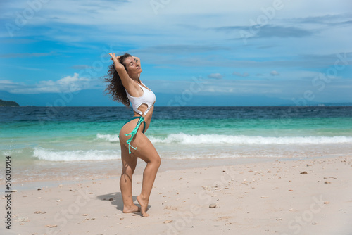 Wallpaper Mural A brunette girl in swimsuit enjoy and walks at the sea. Beautiful female in a bikini on a tropical beach. A curly woman tourist posing at the ocean and enjoys the view during her summer holiday Torontodigital.ca
