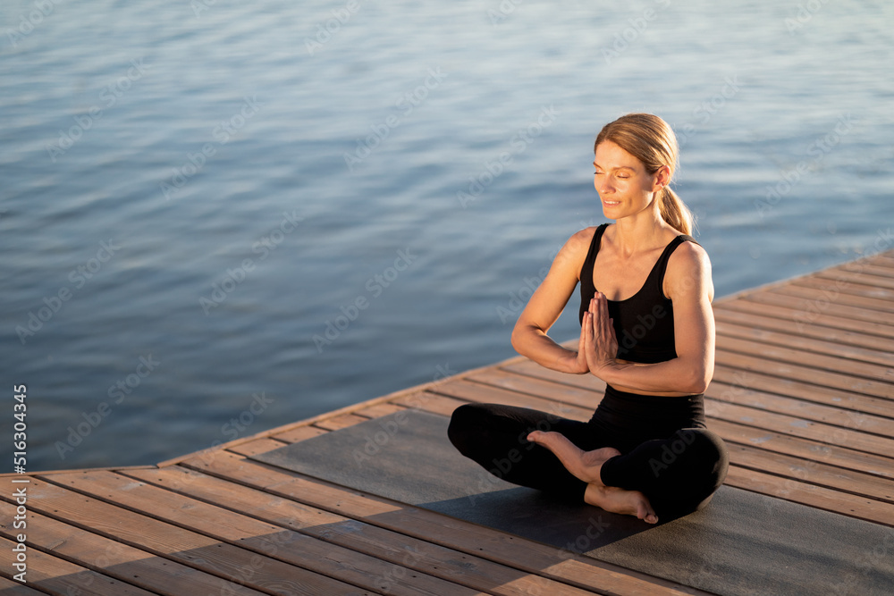 Morning Meditation. Calm Middle Aged Woman Meditating Outdoors On Wooden Pier