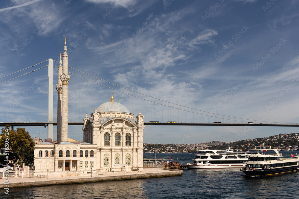 View of cruise tour boats on Bosphorus, historical Ortakoy mosque and bridge in Istanbul. It is a sunny summer day.