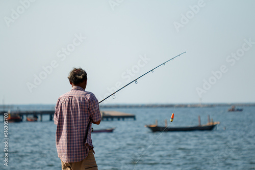 man wearing plaid shirt fishing, that's his hobby on holiday