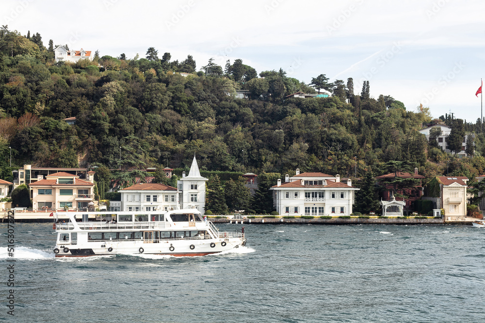 View of cruise tour boat on Bosphorus and historical and traditional mansions in Kandilli area of Asian side of Istanbul. It is a sunny summer day. Beautiful scene.
