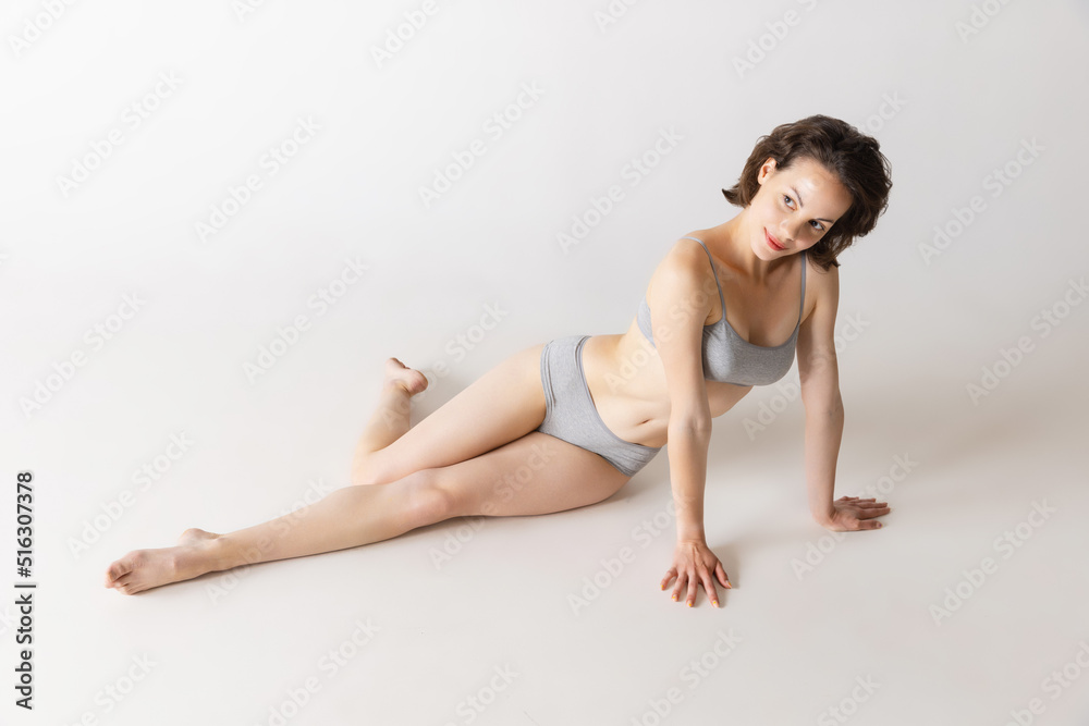 Portrait of young beautiful slim girl in underwear posing isolated over gray studio background. Wellness, wellbeing, fitness, fashion concept.