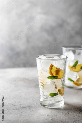 Iced cold lemon mint summer cocktail on gray background with text space on the left