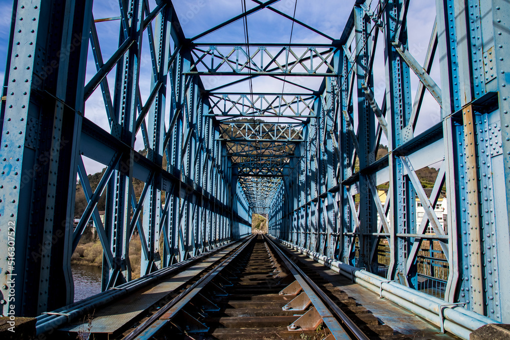 old blue metal bridge and the train track in the town of Os Peares. Ribeira Sacra. Galicia old blue metal bridge and the train track in the town of Os Peares. Ribeira Sacra. Galicia
