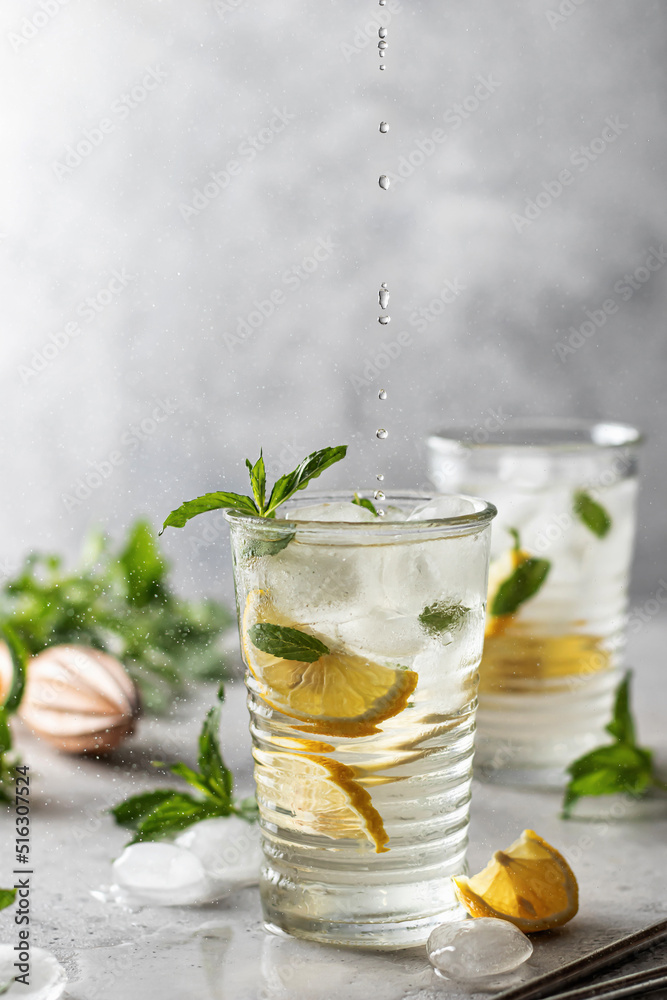Lemonade summer iced cocktail with lemon and mint and metal straws on light gray background with text space Lemonade summer iced cocktail with lemon and mint and metal straws on light gray background with text space