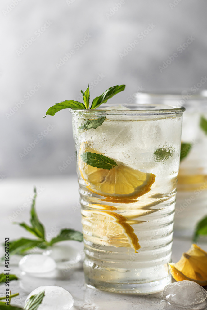 Lemonade or mojito cocktail with lemon and mint, summer iced refreshing drink on gray background Lemonade or mojito cocktail with lemon and mint, summer iced refreshing drink on gray background