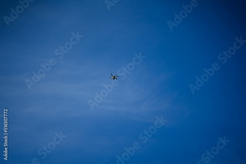 A flying drone rose high into the sky, a quadcopter against the blue sky, a flying car for photo shooting.