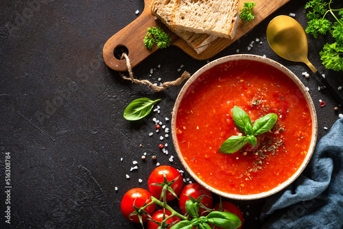 Tomato soup with ingredients on dark background. Traditional vegetable soup. Top view with copy space.