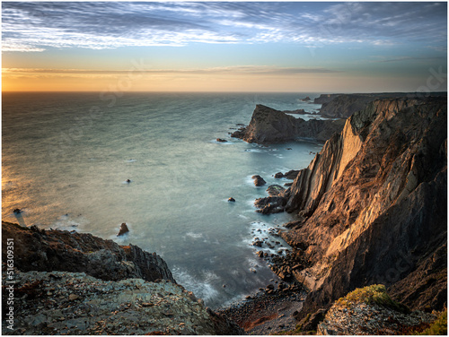 The last rays of light illuminating the seacliffs at Arrifana on the Atlantic coast of Portugal photo