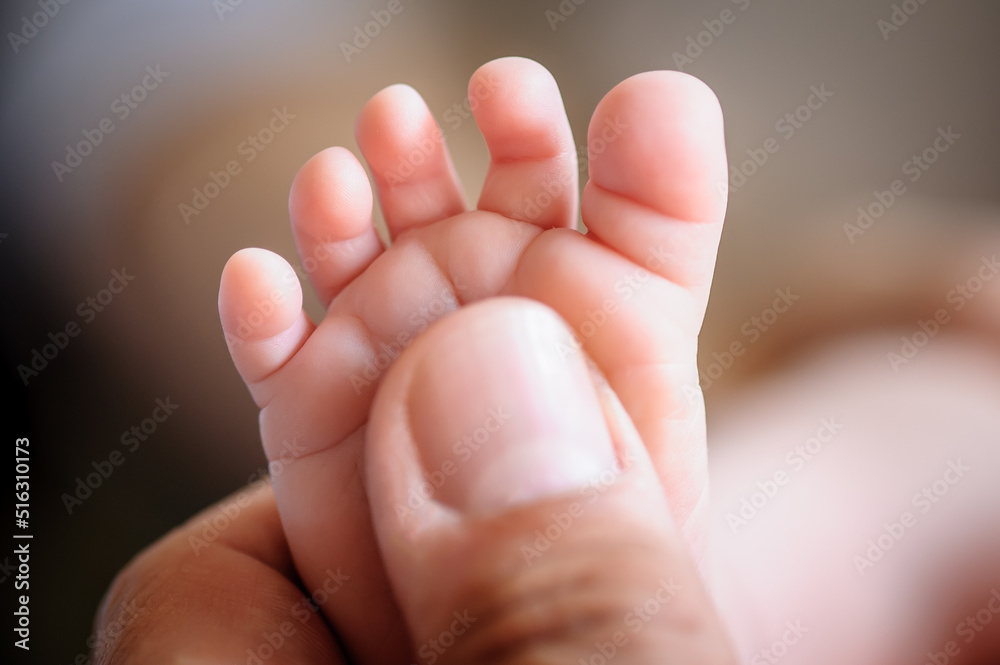 Close-up detail macro view of father thumb and baby small foot. Macro abstract view of sweet baby foot fingers. Soft child skin feet. Love and family emotion Close-up detail macro view of father thumb and baby small foot. Macro abstract view of sweet baby foot fingers. Soft child skin feet. Love and family emotion