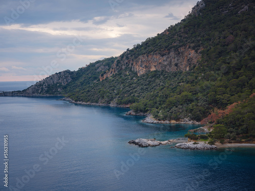 travel to Lagoon in Oludeniz  Fethiye  Turkey. beach near Darbogaz. Winter landscape with mountains  green forest  azure water  beach and cloudy sky