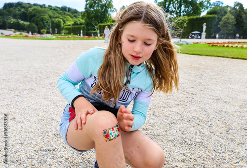 A little girl child fell and hurt her leg. The wound on the knee is sealed with a band-aid.