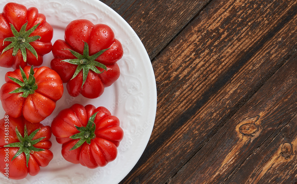 Fresh red tomatoes raf, on white plate on wooden background. Food concept Fresh red tomatoes raf, on white plate on wooden background. Food concept