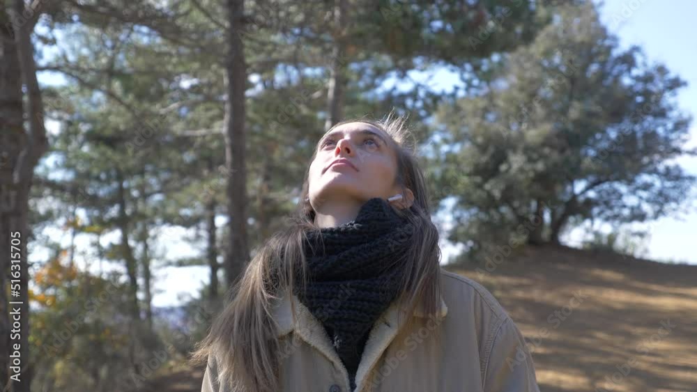 young girl enjoying the nature of a forest while walking, listening to music with her earphones, and making a video call young girl enjoying the nature of a forest while walking, listening to music with her earphones, and making a video call