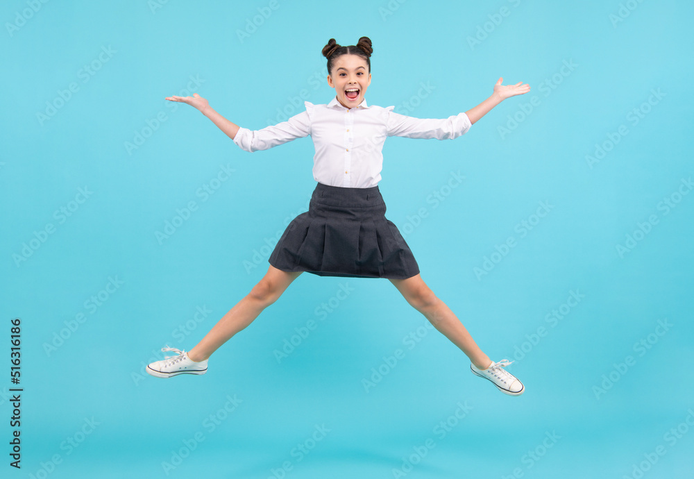 Full length cheerful teenager kid jump enjoy rejoice win isolated on blue background. Small child girl in summer dress jumping. Excited face. Amazed expression, cheerful and glad.