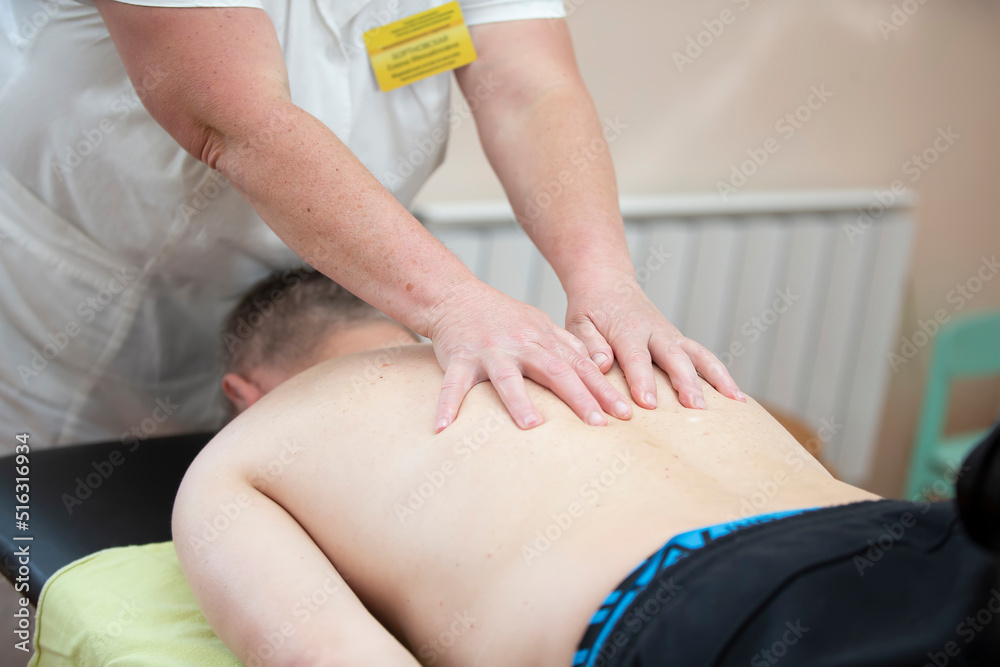Fototapeta premium The doctor makes a back massage to a man patient.