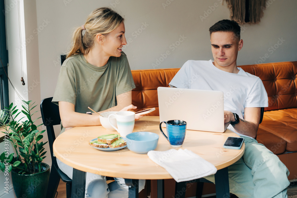 A man and a woman having breakfast use electronic gadgets and a laptop to surf the nets. A man and a woman having breakfast use electronic gadgets and a laptop to surf the nets.