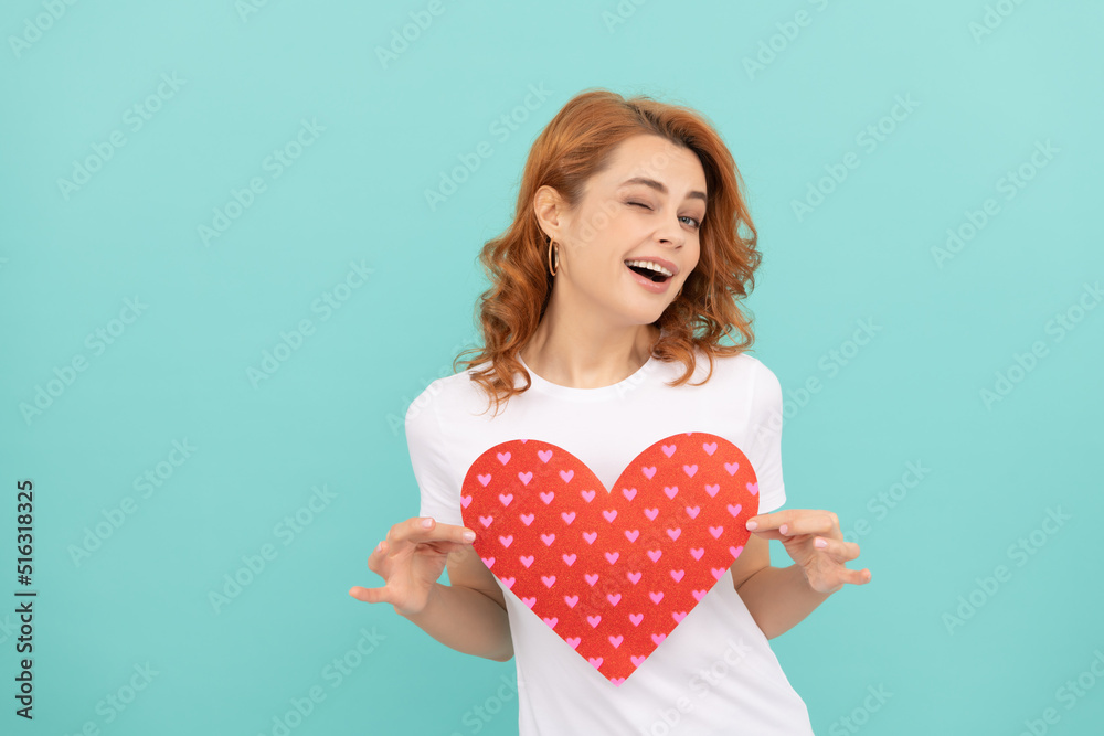 glad redhead woman hold red heart on blue background glad redhead woman hold red heart on blue background