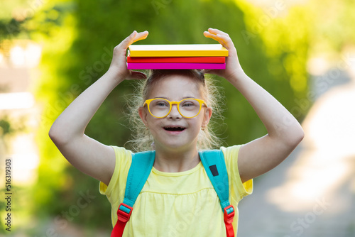 A girl with Down syndrome goes to school with a backpack and books photo