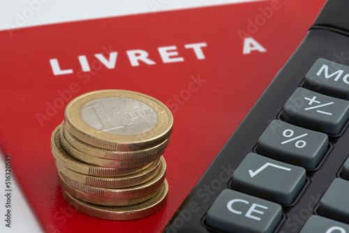 Livret A avec une pile de pièces de monnaie et une calculette. Le livret A est un compte épargne français règlementé dont le taux d'intérêt et le plafond de dépôt sont définis par le gouvernement