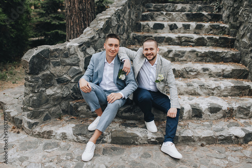 A handsome groom and his best friend go sit on a stone old staircase. Wedding photography, portrait.
