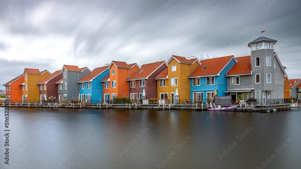 The colorful houses in Reitdiephaven in Groningen Netherlands as a long exposure with smooth water and moving clouds The colorful houses in Reitdiephaven in Groningen Netherlands as a long exposure with smooth water and moving clouds