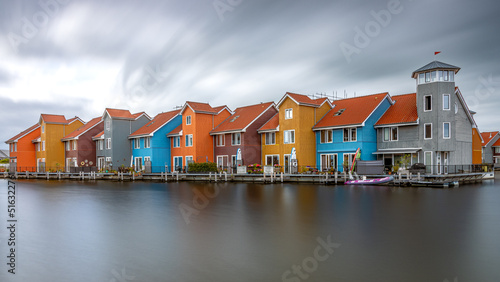 The colorful houses in Reitdiephaven in Groningen Netherlands as a long exposure with smooth water and moving clouds
